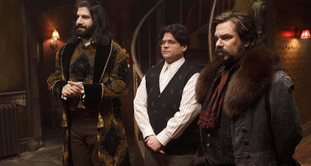 harvey standing in the middle to two guys, a scene from what do we do in the shadows 